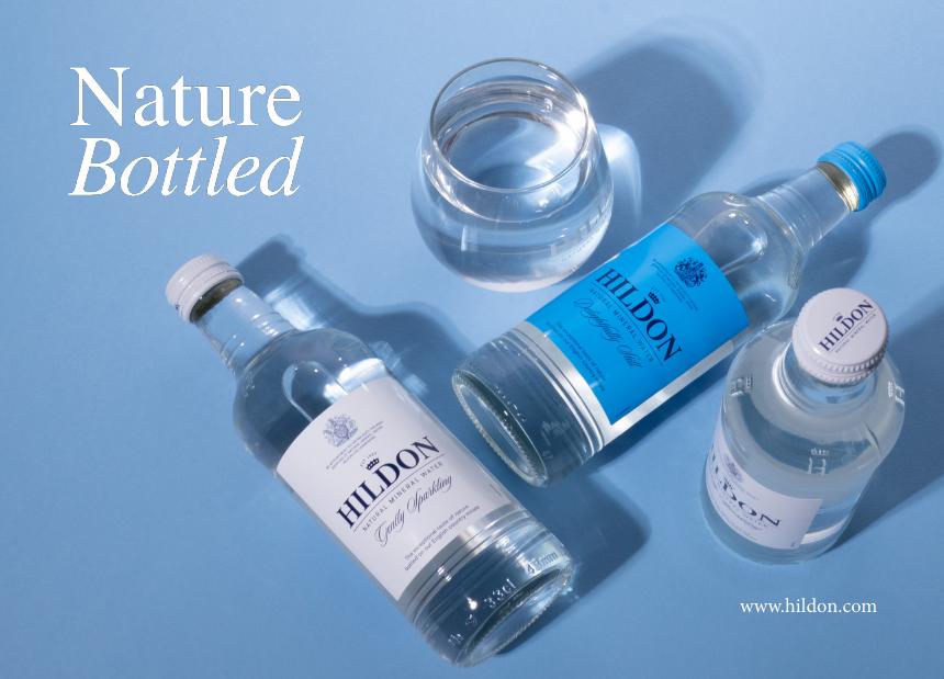 Botellas Hildon Still y Sparkling junto a un vaso de agua